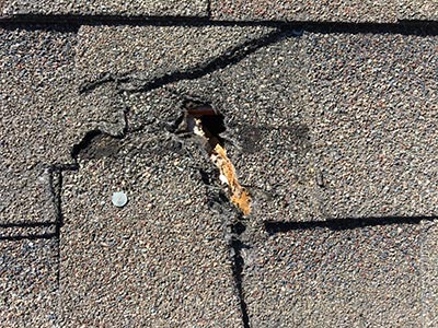 a hole in an asphalt shingle roof